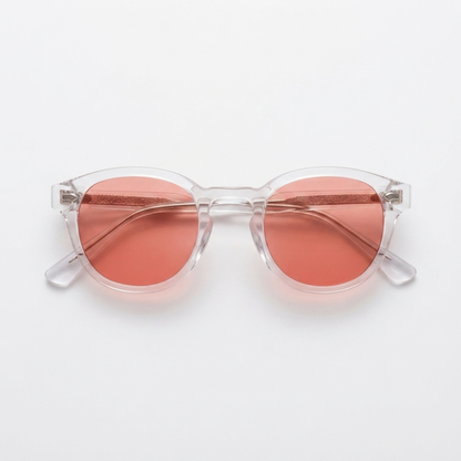 Round sunglasses with translucent clear frames and rose pink lenses, shown from a top-down view on a light gray background.
