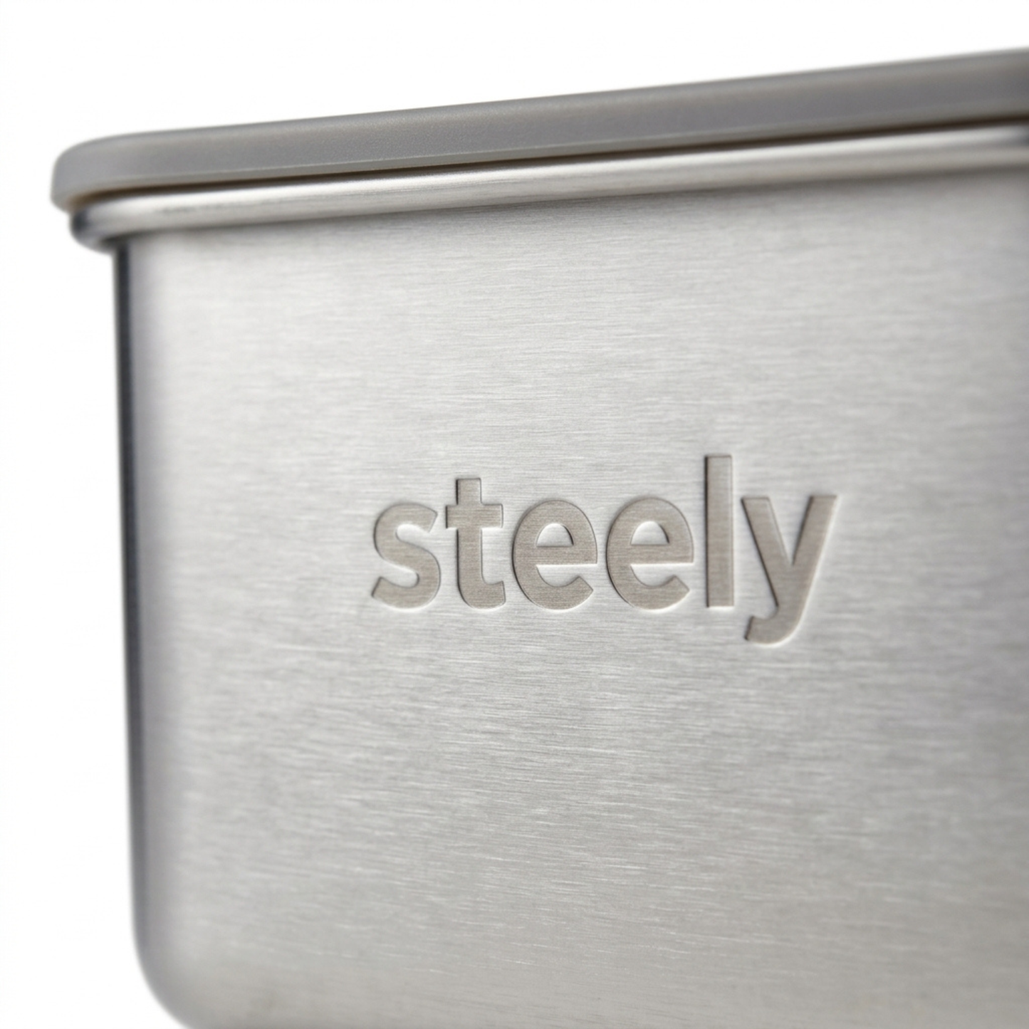 Close-up of a brushed stainless steel container with the brand name 'steely' debossed on the front, set against a clean white background.