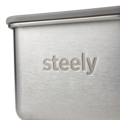 Close-up of a brushed stainless steel container with the brand name 'steely' debossed on the front, set against a clean white background.